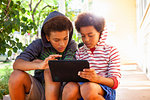 Two brothers using touchscreen on digital tablet in garden