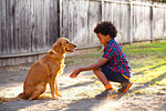 Boy training dog to give paw in garden