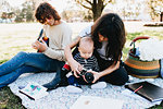 Couple with baby on picnic blanket in park