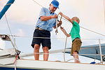 Boy and grandfather knotting rope on sailboat