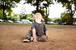 Male toddler sitting in park looking up