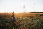 Senior male farmer walking across remote field at dusk, Plattsburg, Missouri, USA