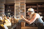 Mid adult woman photographing cheeses on smartphone in organic grocery