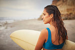 Rear view of young woman carrying surfboard on beach, San Diego, California, USA