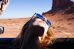 Woman leaning back out of car window, Monument Valley, Utah, USA