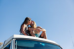 Couple sitting on roof of camper van, kissing