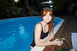 Portrait of young woman with long red hair in swimming pool at dusk