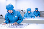 Female workers inspecting flex circuits in flexible electronics factory clean room