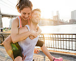 Young male runner piggybacking girlfriend, New York, USA