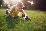 Girl kneeling on grass stroking Boston Terrier puppy