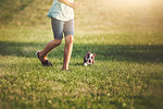 Waist down of girl running on grass with Boston Terrier puppy