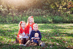 Four children family on autumn leaf covered grass posing for photograph smiling