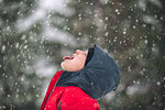 Side view of boy sticking out tongue catching snowflakes
