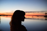 Side view of young woman in silhouette looking out over water