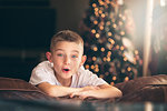 Portrait of excited boy on sofa in front of christmas tree