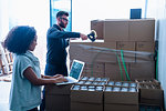 Colleagues in warehouse sealing up cardboard boxes of beer with sticking tape, organising delivery