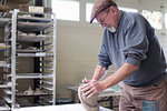 Side view of potter in workshop kneading clay