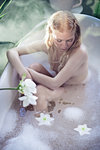 Nude young woman relaxing in bathtub, elevated view