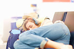 Young woman at airport, sleeping on seating in departure lounge