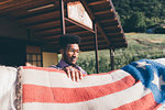 Young man putting american flag blanket on horse's back at ranch