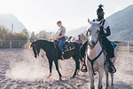 Young hipster man and woman riding horses in rural equestrian arena, Primaluna, Trentino-Alto Adige, Italy
