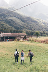 Young adult hikers hiking across field, rear view, Primaluna, Trentino-Alto Adige, Italy