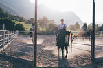 Young adults horse riding in rural equestrian arena, Primaluna, Trentino-Alto Adige, Italy