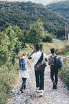 Young adult hiker friends hiking along rural cobbled road, rear view, Primaluna, Trentino-Alto Adige, Italy