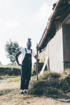 Cool young male agricultural worker with pitchfork, full length portrait