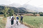 Three young adult friends hiking along dirt track, rear view, Primaluna, Trentino-Alto Adige, Italy