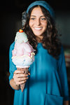 Stylish young woman in blue knit hat holding large ice cream cone, shallow focus