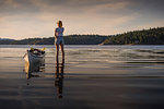 Young female kayaker standing looking out over lake, Quadra Island, Campbell River, Canada