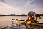 Young female kayaker unpacking kayak, Quadra Island, Campbell River, Canada