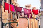 Red and pink clothing on clothesline outside traditional houses, Venice, Veneto, Italy