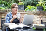 Pregnant mid adult woman looking at laptop on patio table