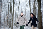 Young couple walking hand in hand in snow covered forest, Ontario, Canada