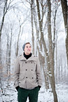 Young man standing in snow covered forest, Ontario, Canada