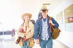 Young couple at airport, carrying backpacks, setting off on journey