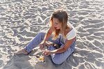 Young woman peeling fruit on beach