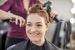 Hairdresser blow drying customer's hair in salon