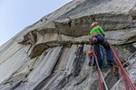 Young female rock climber climbing rock face, low angle view, The Chief, Squamish, British Columbia, Canada