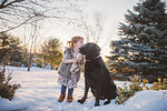 Female toddler with red hair playing in snow with dog, Keene, Ontario, Canada