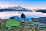 A couple admires the sunrise at the lake of Manzina, Valfurava, Valtellina, Italy, Europe