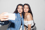 Teenage twin girls taking selfie with smart phone