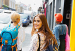 Portrait smiling, confident young woman with backpack on urban sidewalk