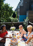 Portrait smiling young women friends enjoying brunch on sunny apartment balcony