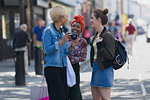Young women friends with camera on urban sidewalk