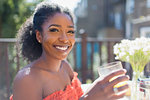 Portrait smiling, confident young woman drinking orange juice on sunny balcony