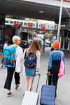 Young women friends with suitcases outside urban train station