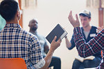 Men with bible praying with arms raised in prayer group